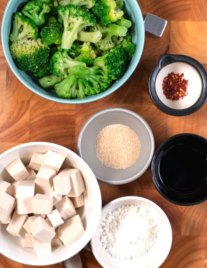 Ingredients needed to make Tofu and Broccoli collected on a wooden board.