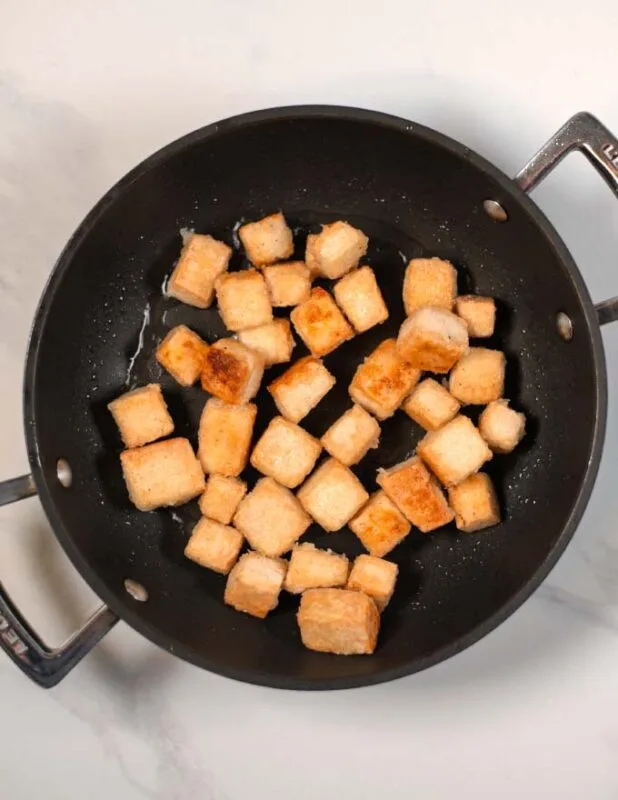Crispy fried tofu cubes in a pan.