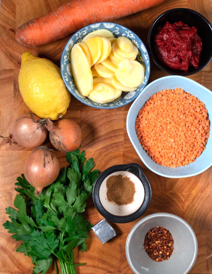 Ingredients needed to make Turkish Lentil Soup are collected on a wooden board.
