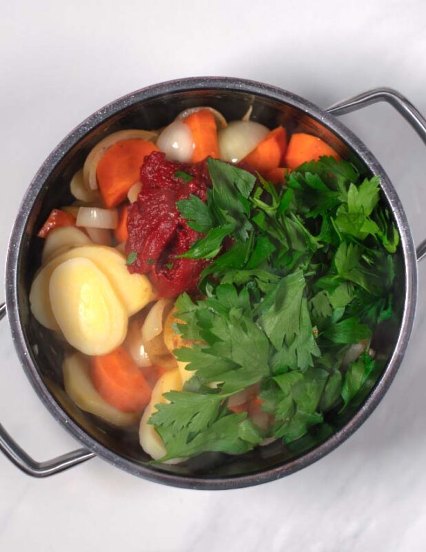 Tomato paste, parsley and spices are given to the soup pot.