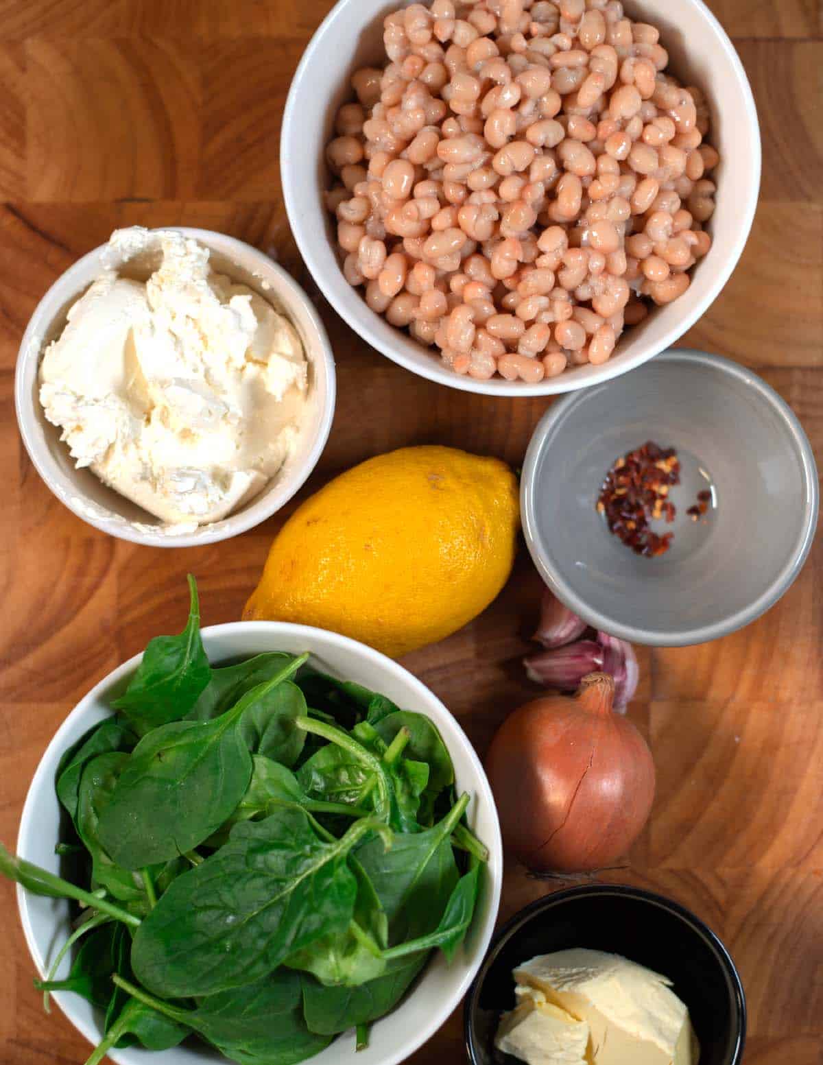 Ingredients needed to make Beans and Greens are collected on a cutting board.