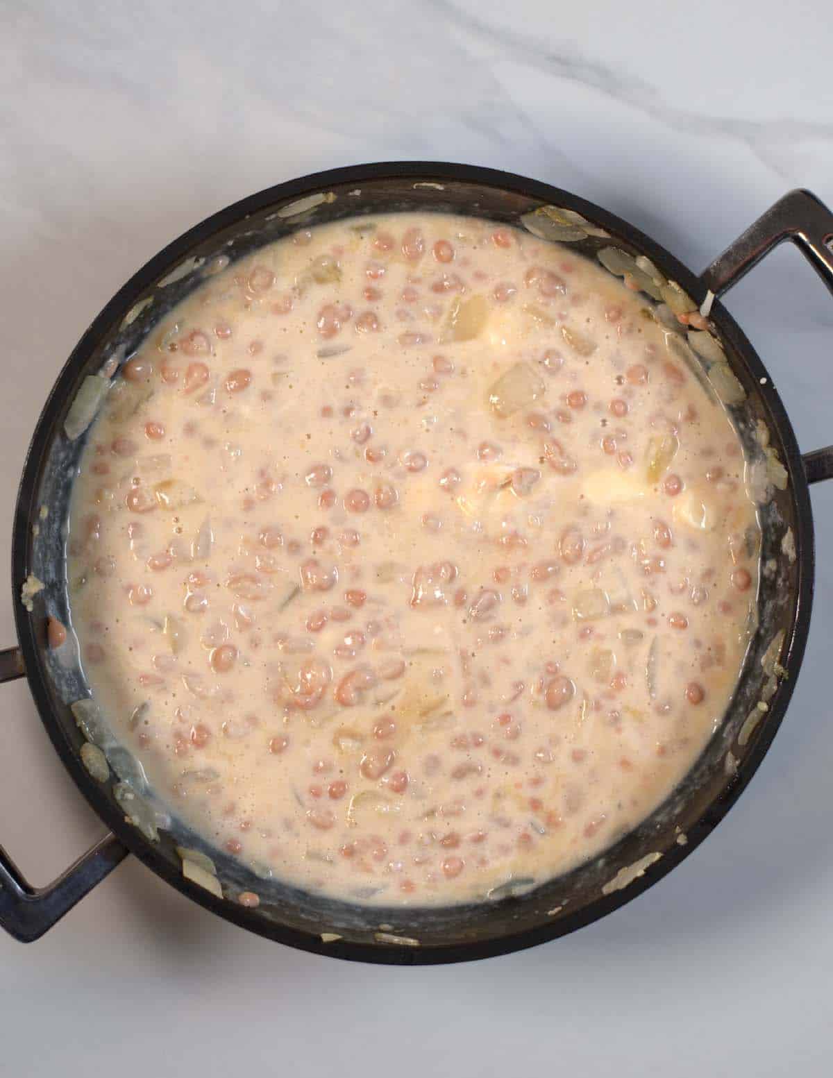 Vegan sour cream has been mixed into the bean-onion mixture in the pan.