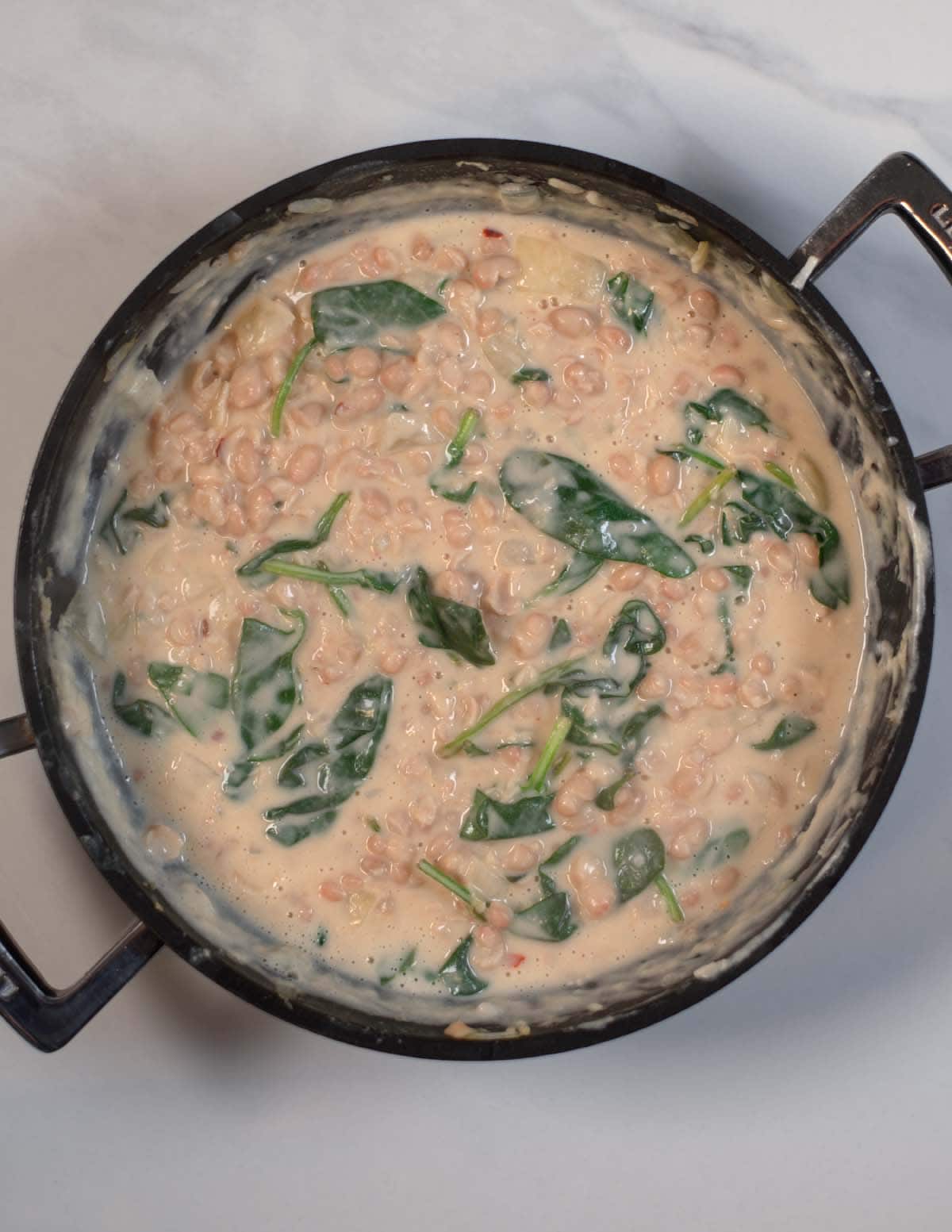 Ready creamy Beans and Greens in a pan.