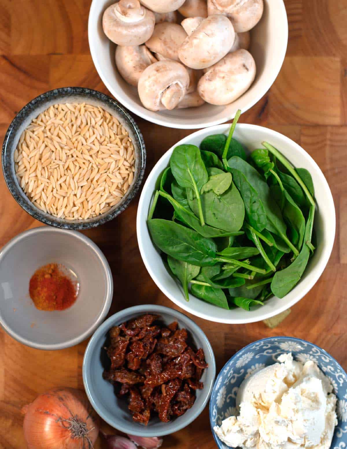 Ingredients needed to make Marry Me Orzo collected on a wooden board.