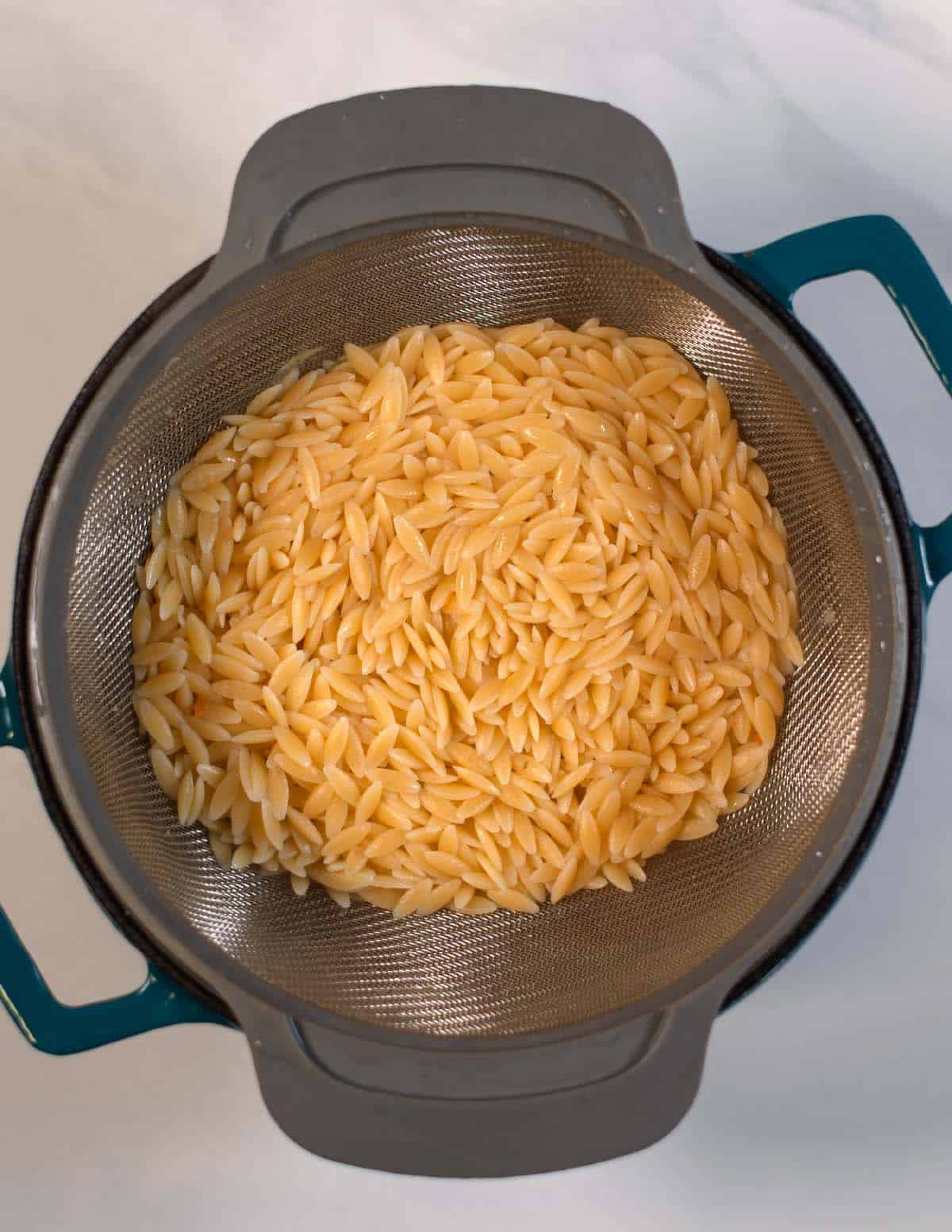 Precooked orzo in a colander.