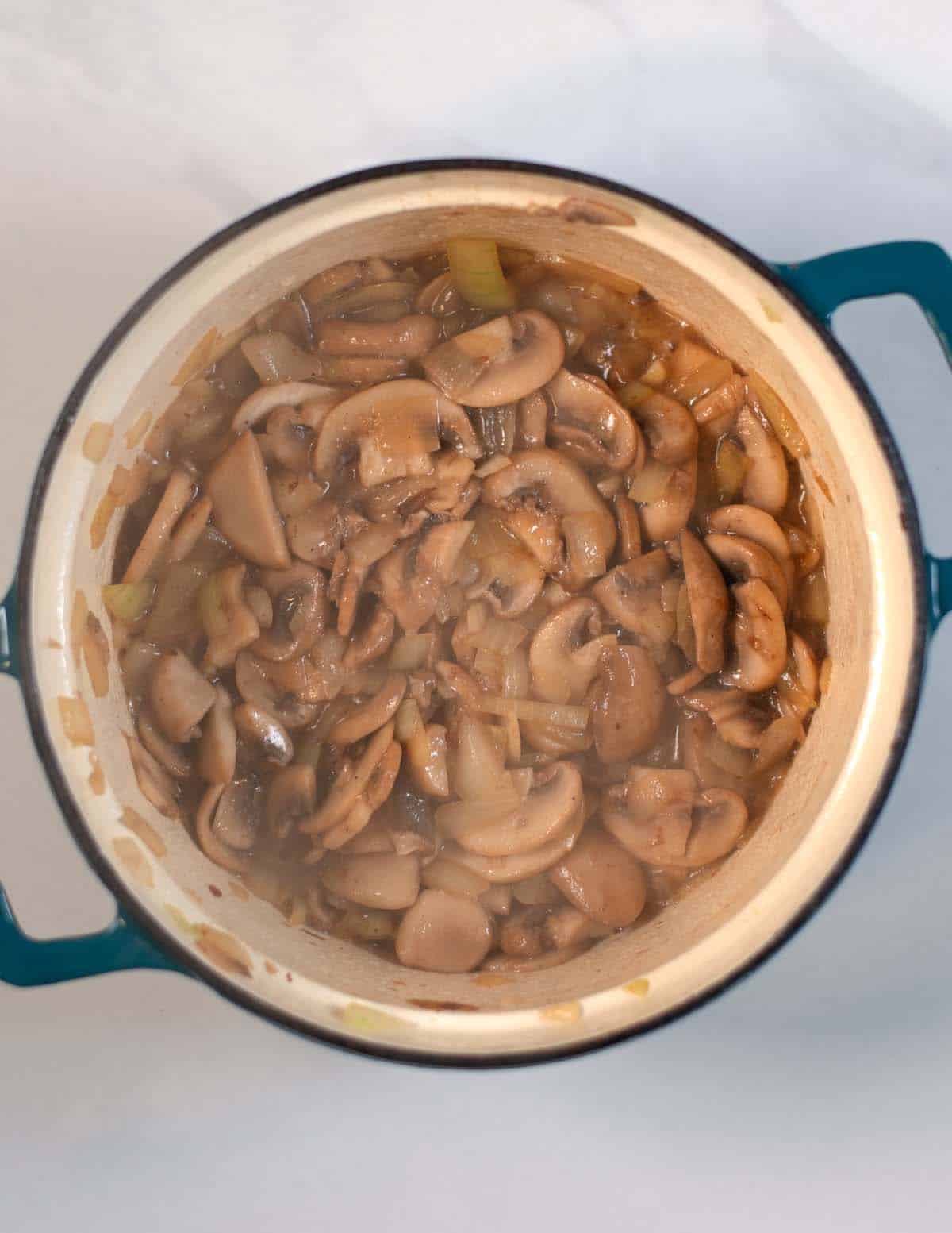 Onions and mishrooms are cooked in a Dutch oven.