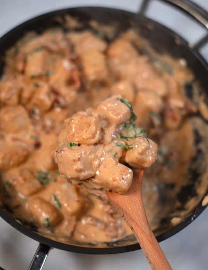 A wooden spoon lifts Marry Me Tofu from the pan.