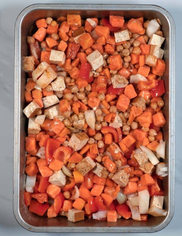 Cut vegetables are tossed in vegetable oil and spices before roasting in the oven.