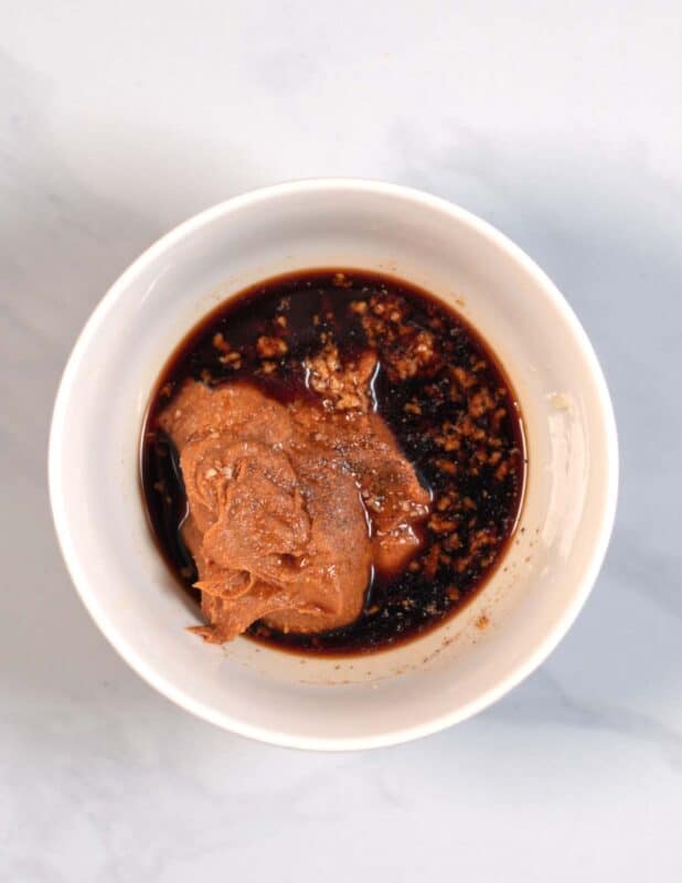 Ingredients for the creamy peanut sauce are given into a white mixing bowl.