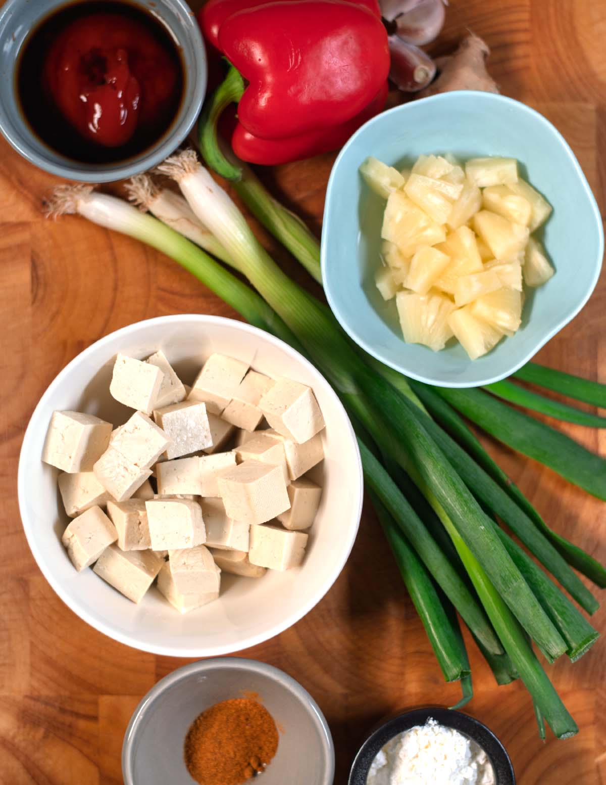Ingredients needed to make Sweet and Sour Tofu are collected on a wooden board.