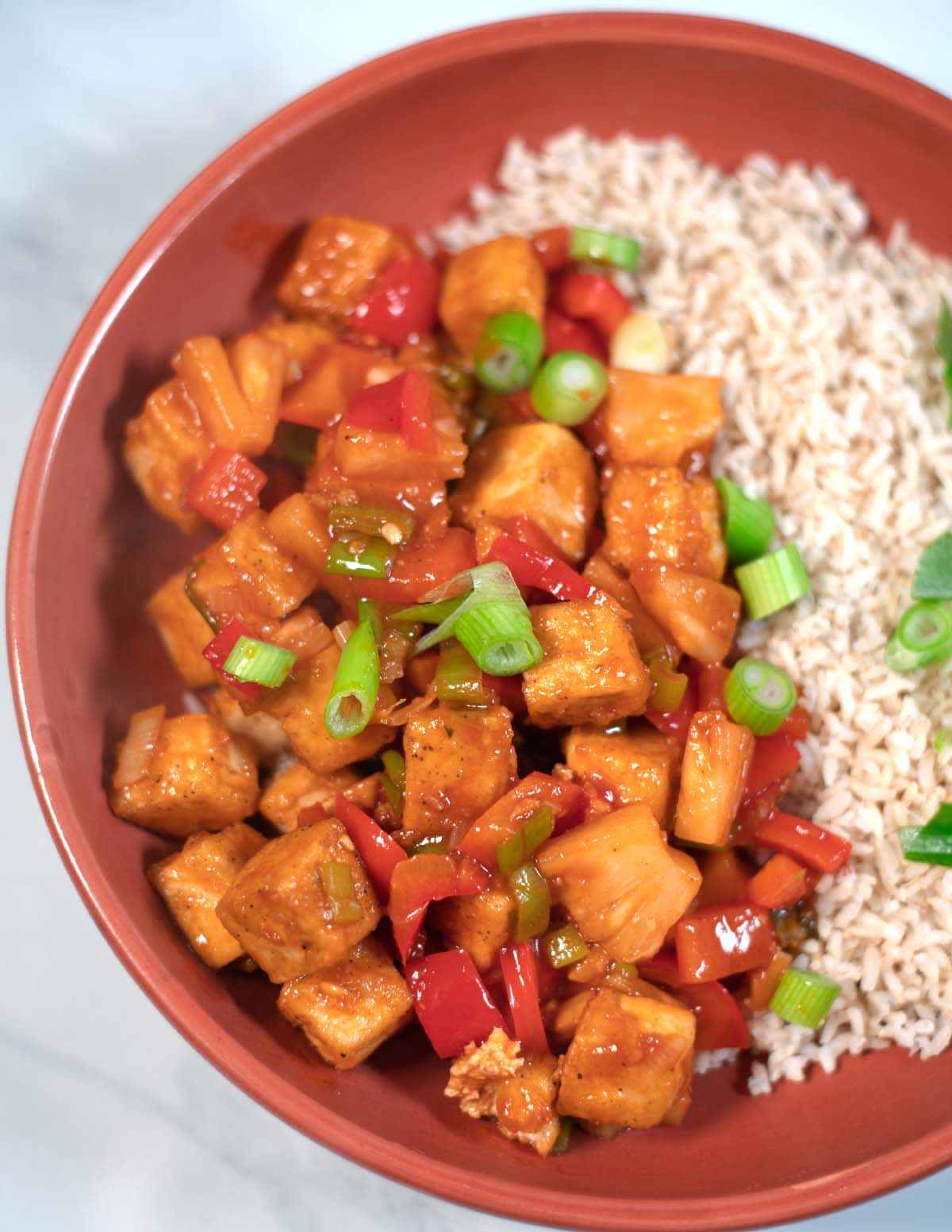 Closeup on a serving of Sweet and Sour Tofu, garnished with fresh scallions.