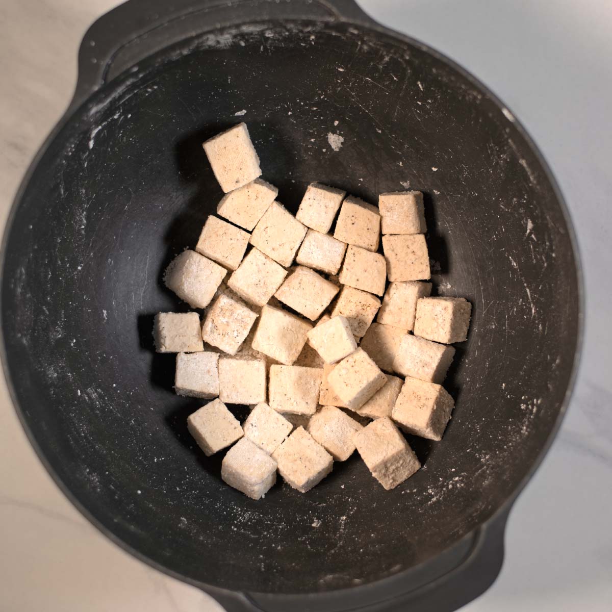Dried tofu cubes are coated in cornstarch.