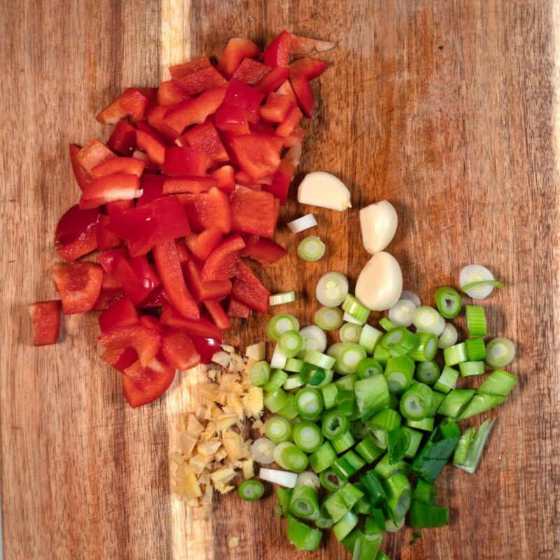 Finely cut vegetables and spices on a cutting board.