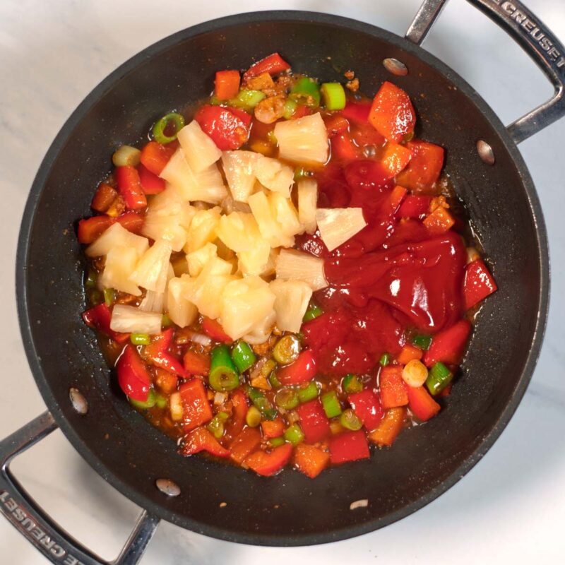 Cut pineapple and sauce ingredients are added to the pan with fried vegetables.