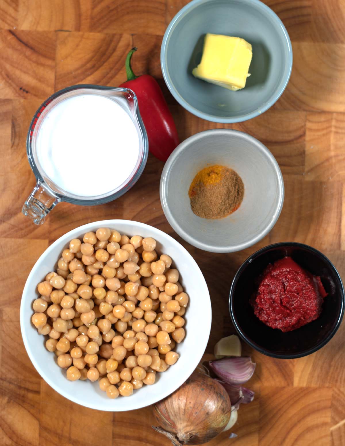 Ingredients needed to make Butter Chickpeas collected on a wooden board.