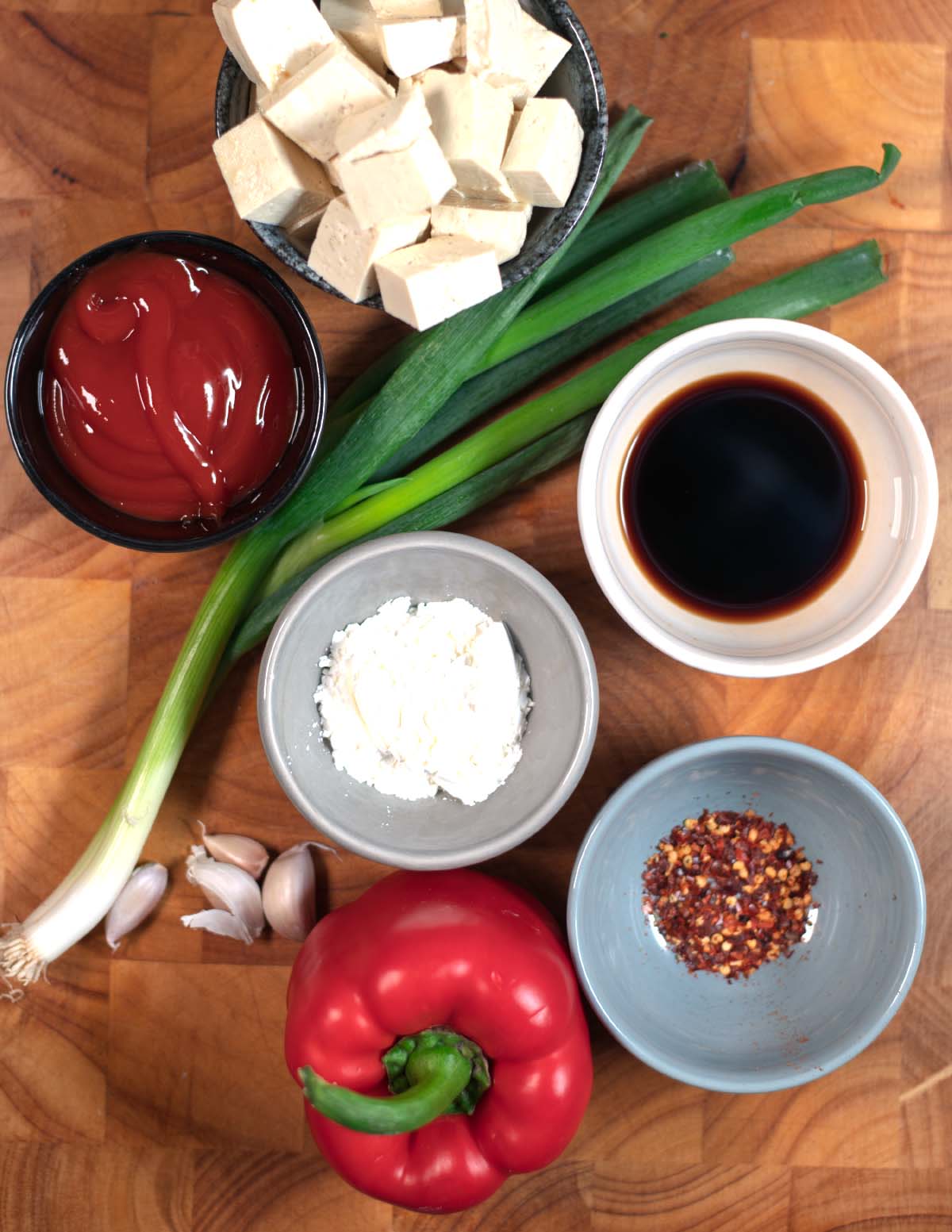 Ingredients needed to make Chili Tofu are collected on a wooden board.