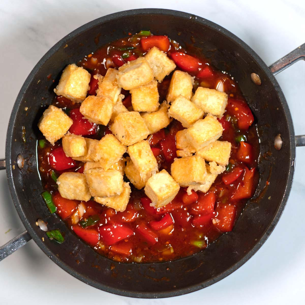 Prefried tofu cubes are given back into the frying pan.