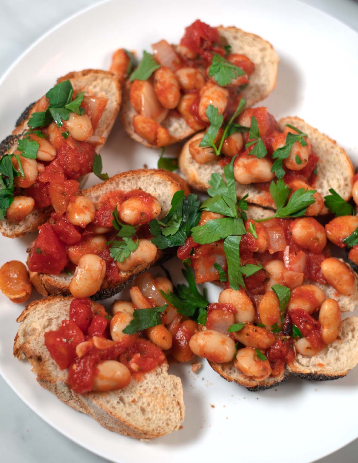 Fresh serving of Gigantes Plaki on bread with parsley garnish.