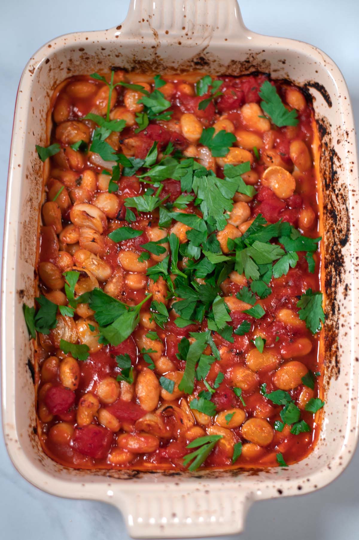 A zoom onto a baking dish with ready Gigantes Plaki.