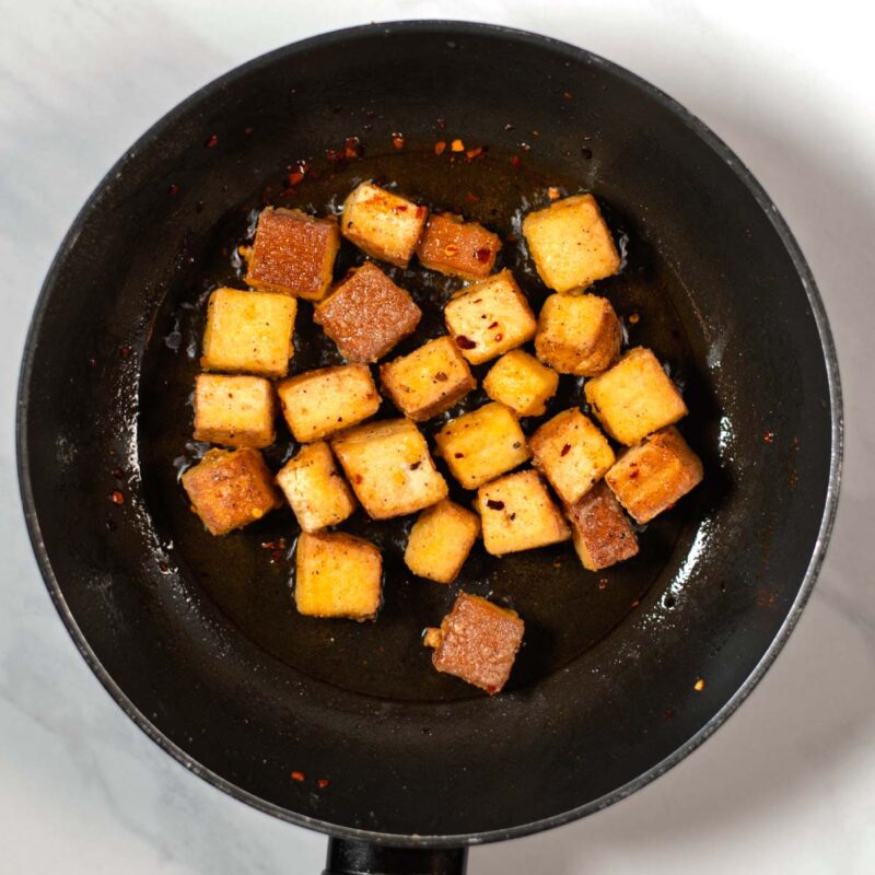 Cross fried tofu cubes in a pan.