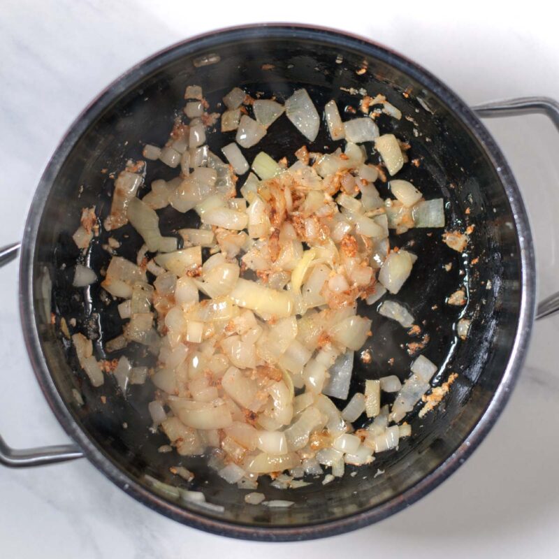 Onions and garlic are roasted in a pot.