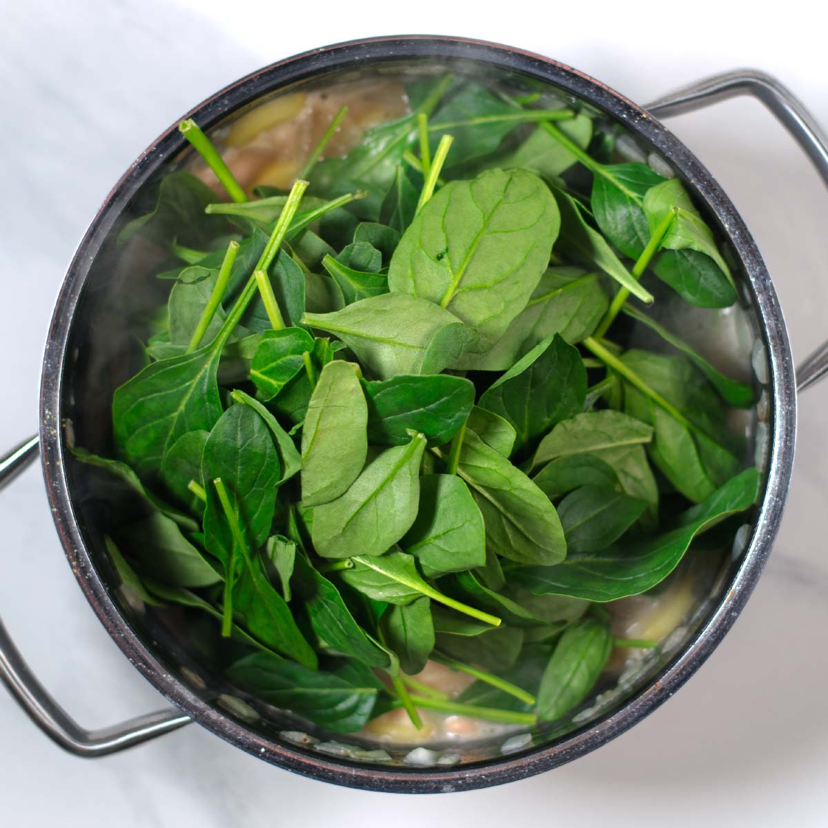 Vegan sour cream and fresh spinach are the final ingredients for Million Dollar Soup that are added to the pot.