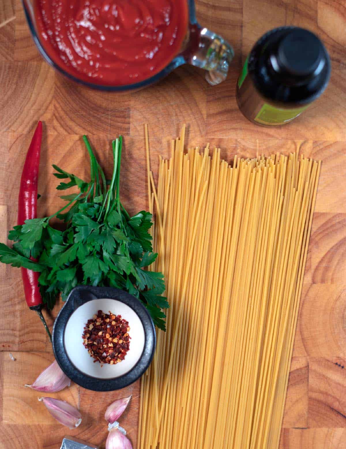 All simple ingrdients needed to make Spaghetti All'Assassina are collected on a wooden board.