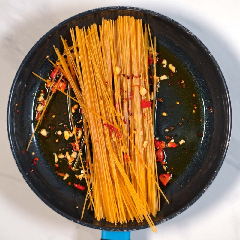 Uncooked spaghetti are covered in smoky oil and also browned slighly.