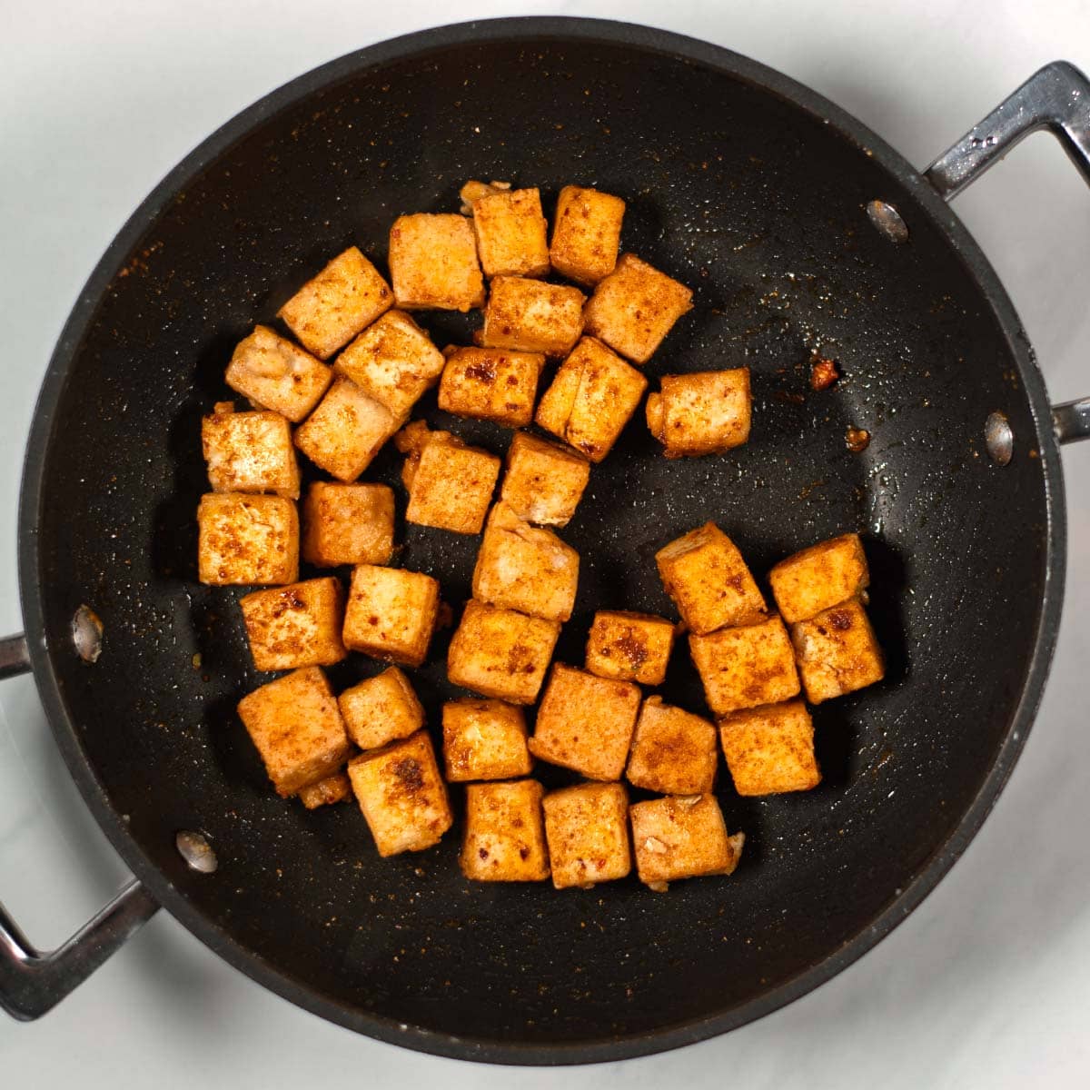 Crispy spiced tofu cubes in a pan.