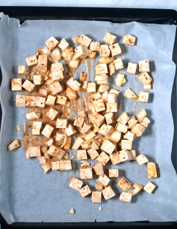 Marinated tofu cubes are given on a sheet pan.