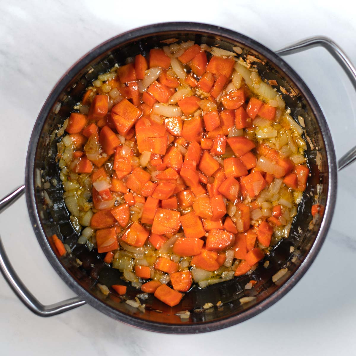 Diced onions and chopped carrots are sauteed in olive oil.