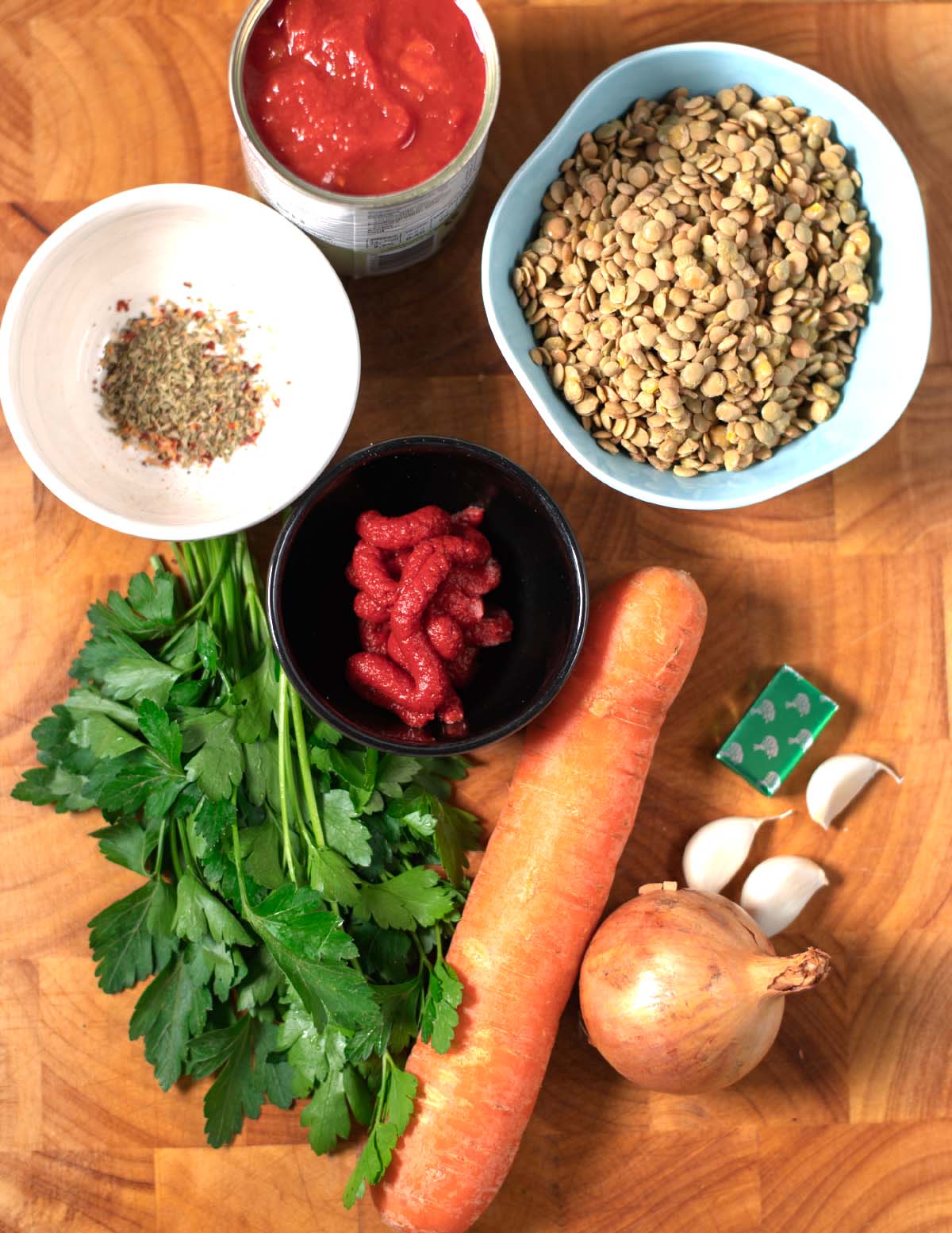 Ingredients needed to make Italian Lentil Soup without Celery are collected on a wooden board before preparation.