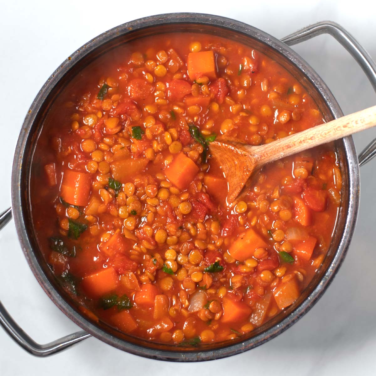 Ready Italian Lentil Soup with a wooden spoon.