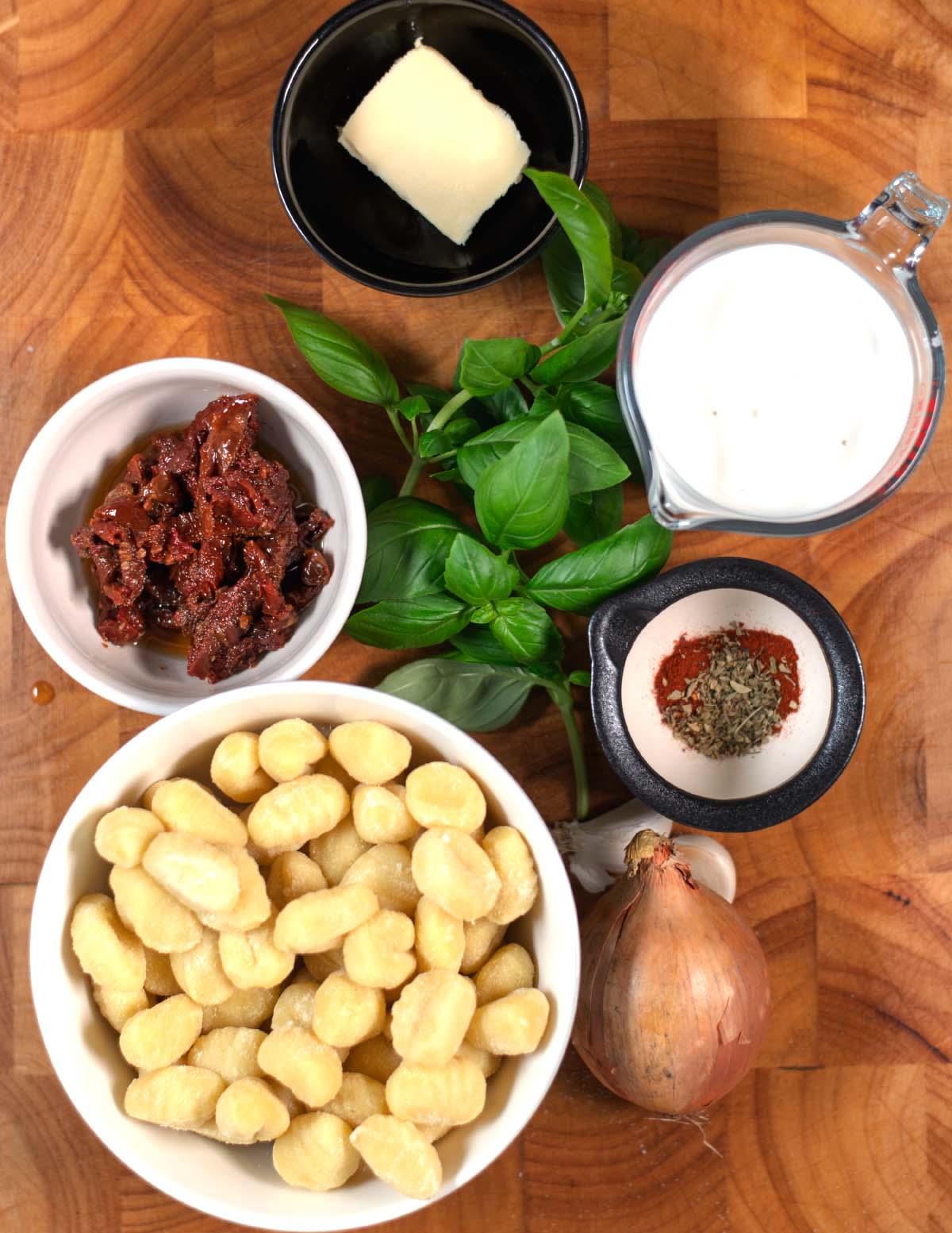 Ingredients needed to make Marry Me Gnocchi are collected on a wooden board.