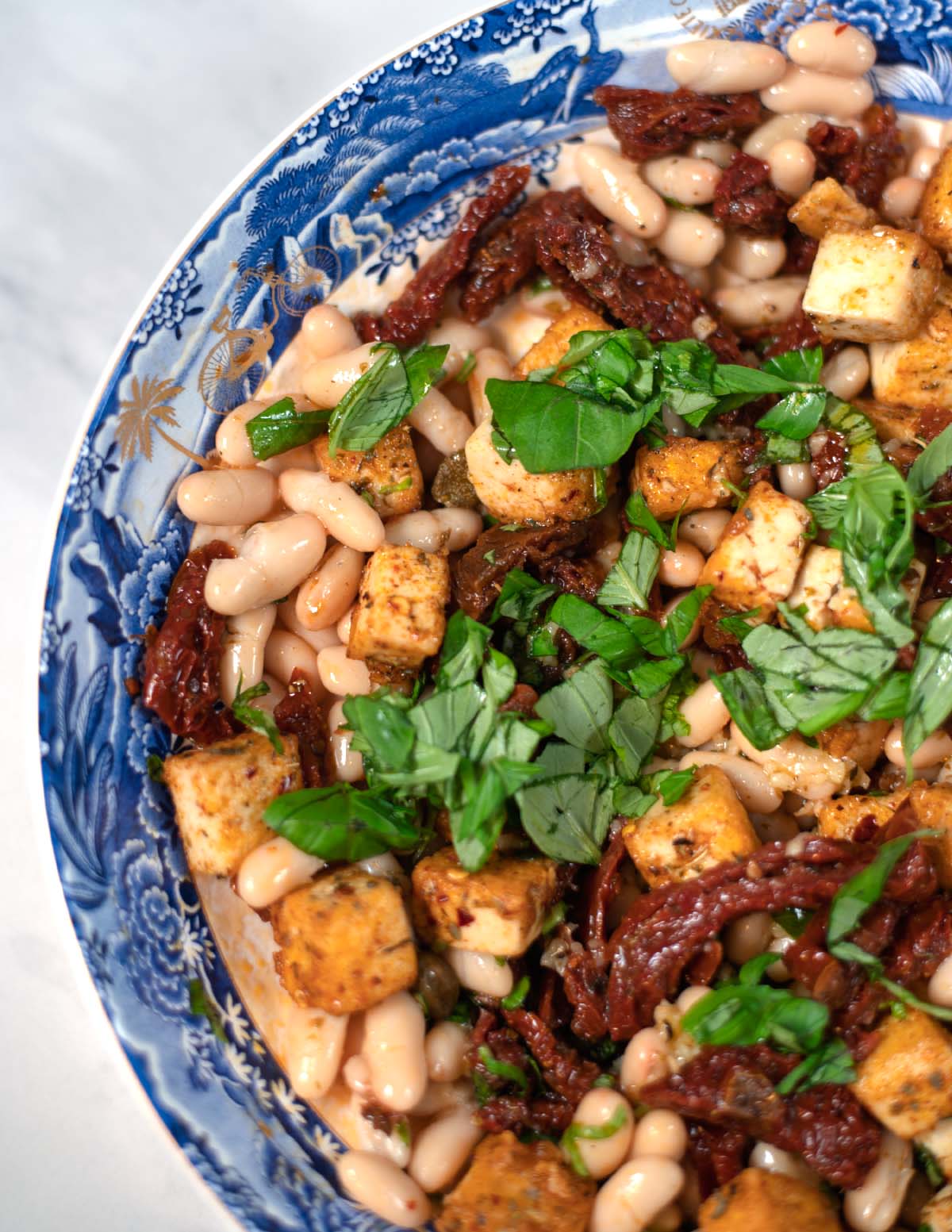 Beans, tofu, and sundried tomatoes in a serving bowl.
