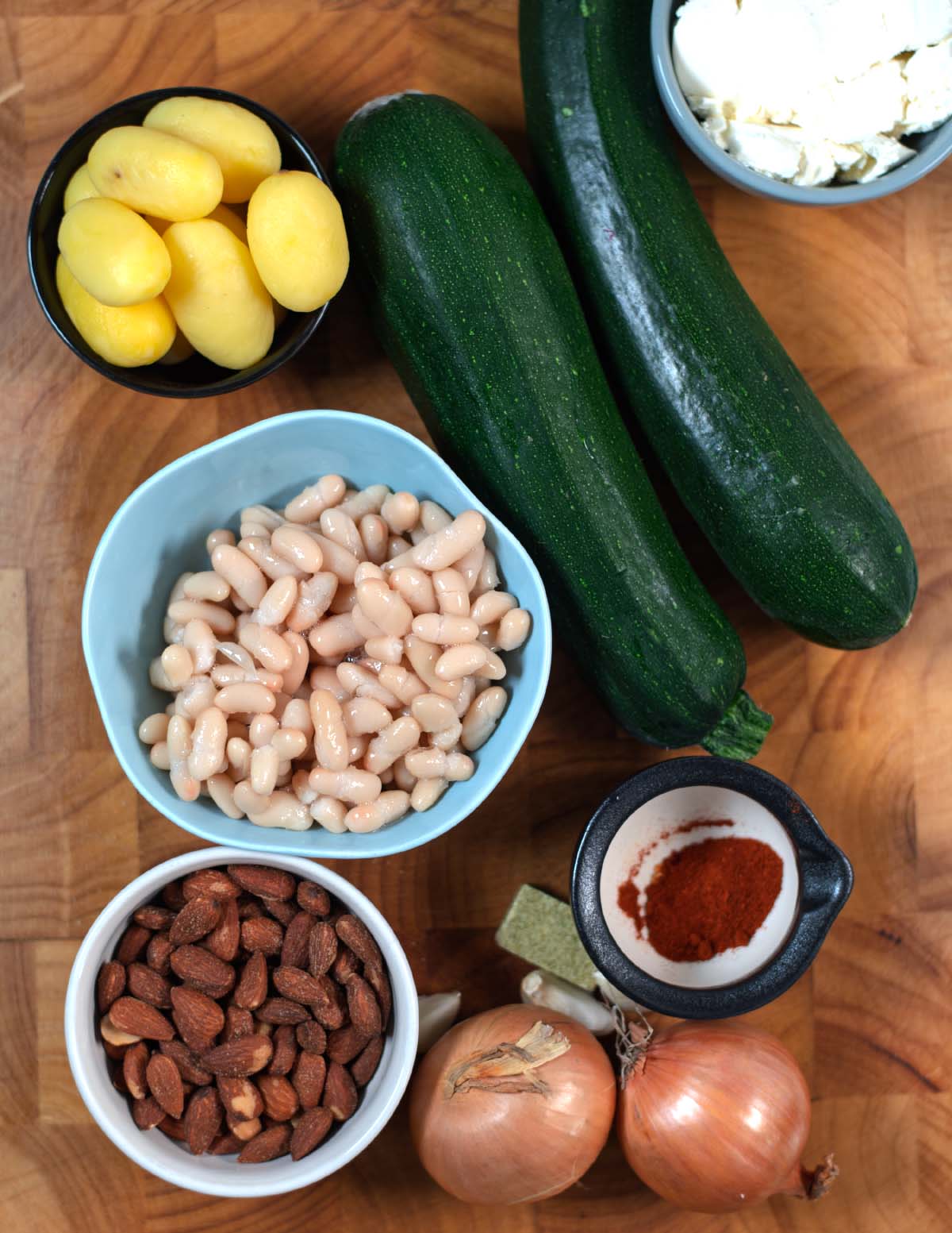 Ingredients needed to make Zucchini Soup collected on a wooden board.
