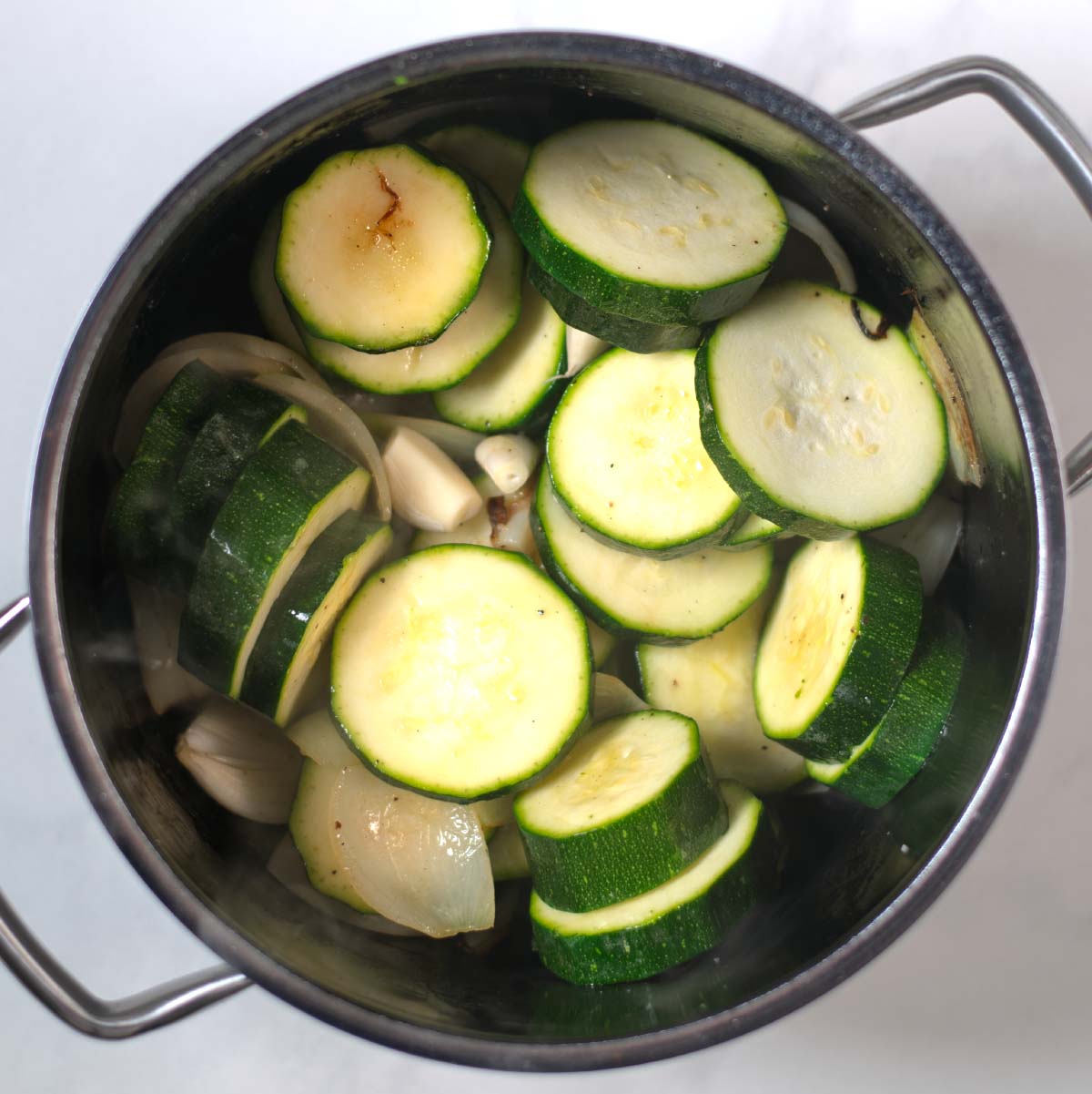 Zucchini slices are fried in a large pot.