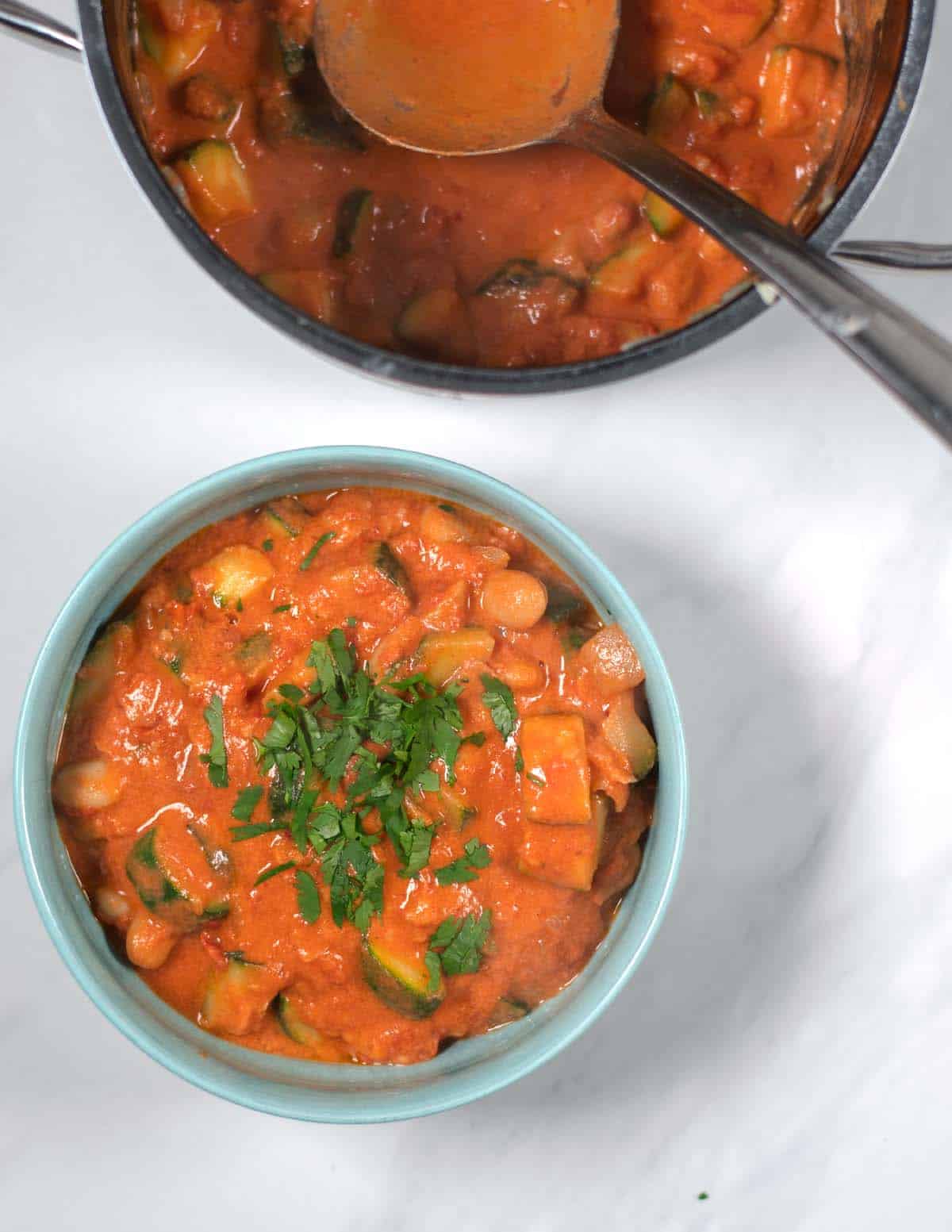 A large serving of Zucchini Stew in a serving bowl, with the pot in the background.