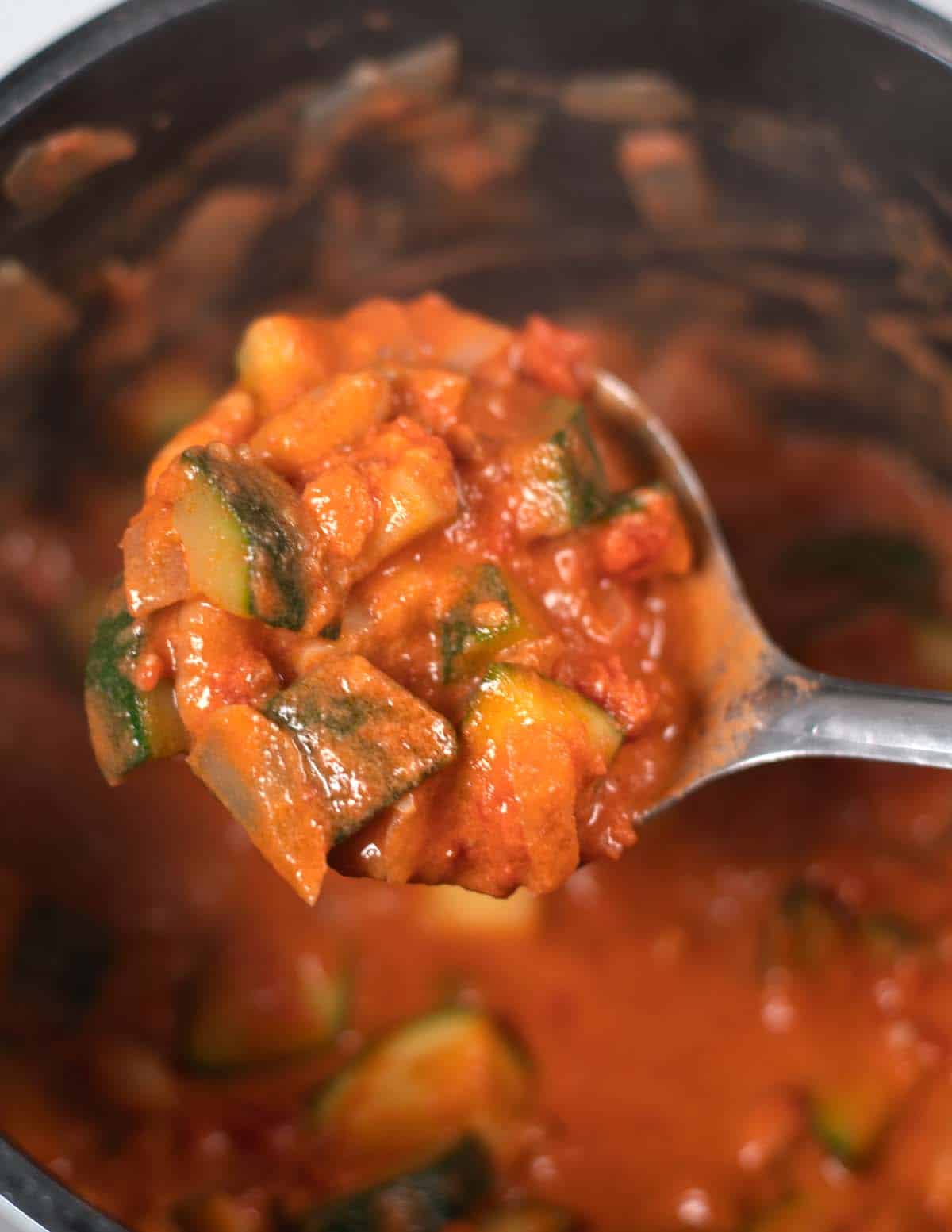 A large spoon of Zucchini Stew is lifted from the pot.