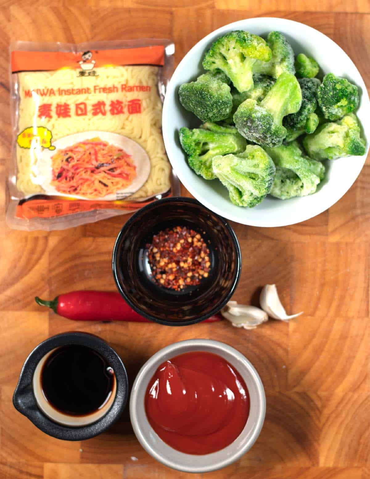 Ingredients needed to make Chili Noodles are collected on a wooden board.