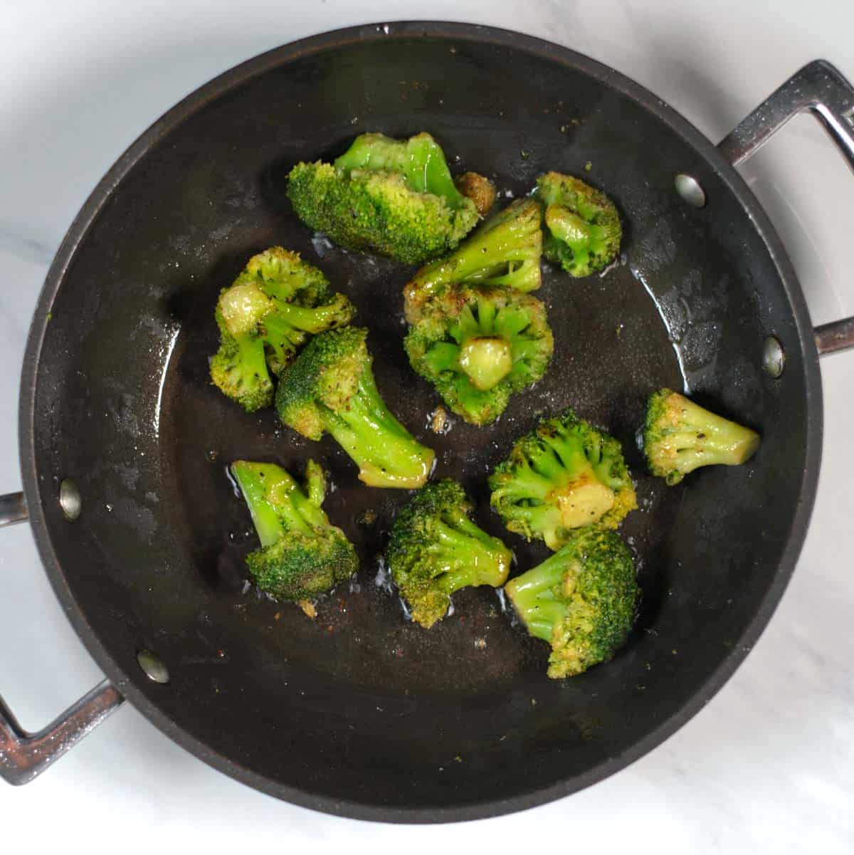 Broccoli florets are roasted in a pan.
