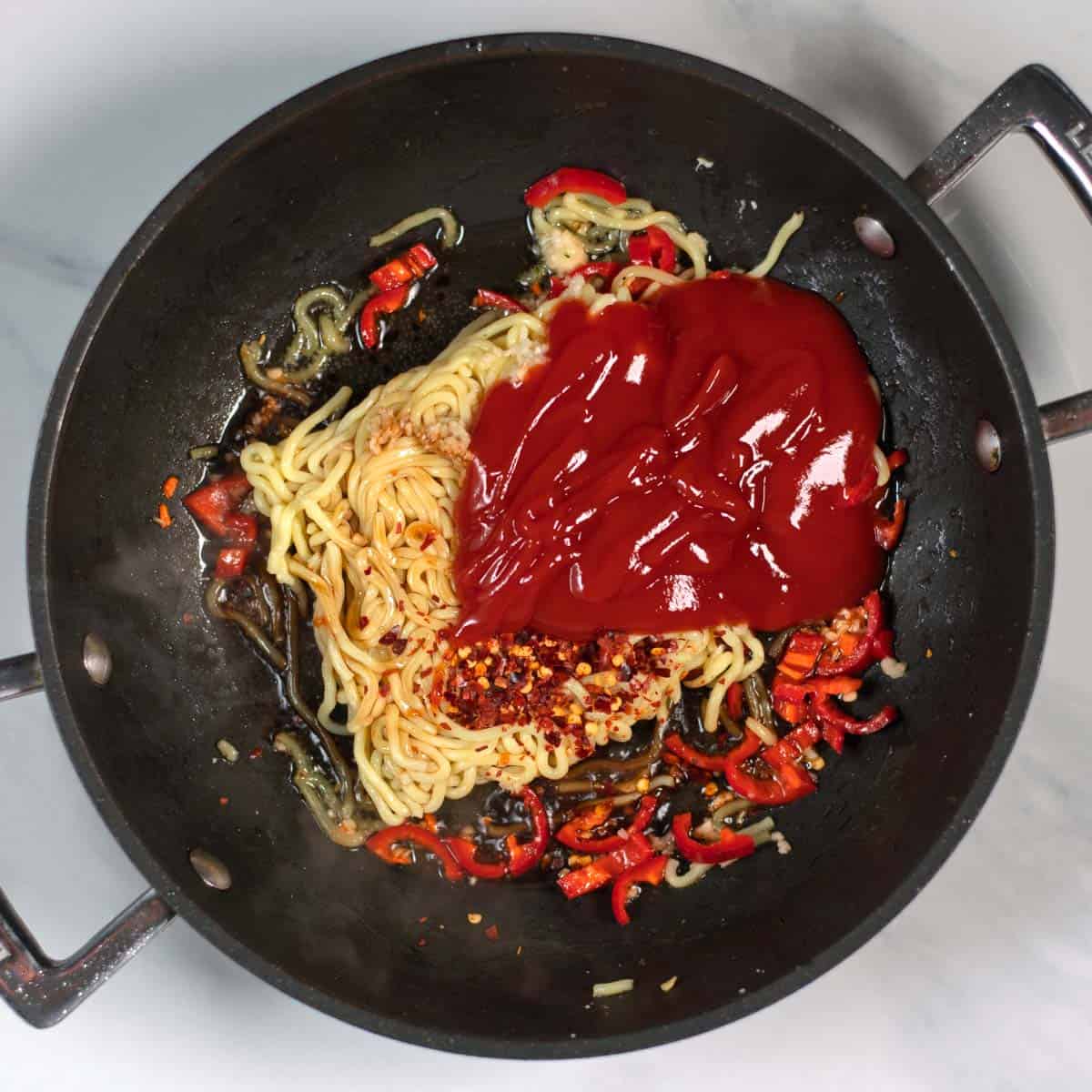 Noodles and all spicy sauce ingredients are given into a pan.