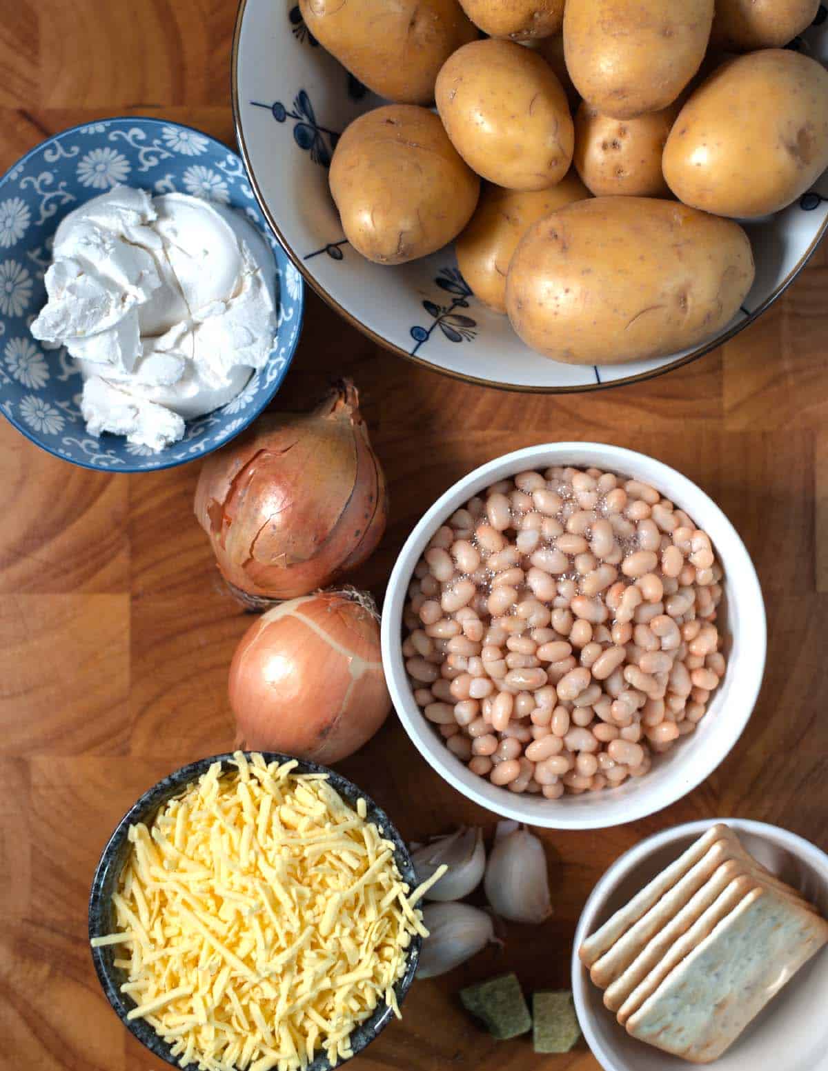 Ingredients needed to make Million Dollar Potatoes are collected before preparation on a wooden board.