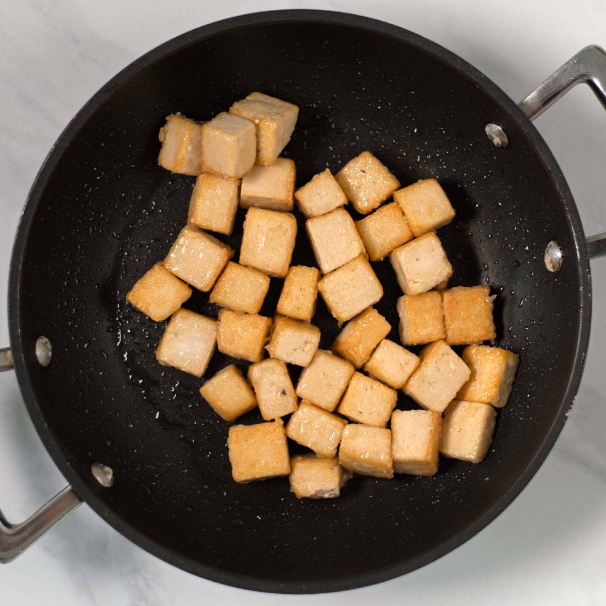 Crispy tofy cubes in a frying pan.