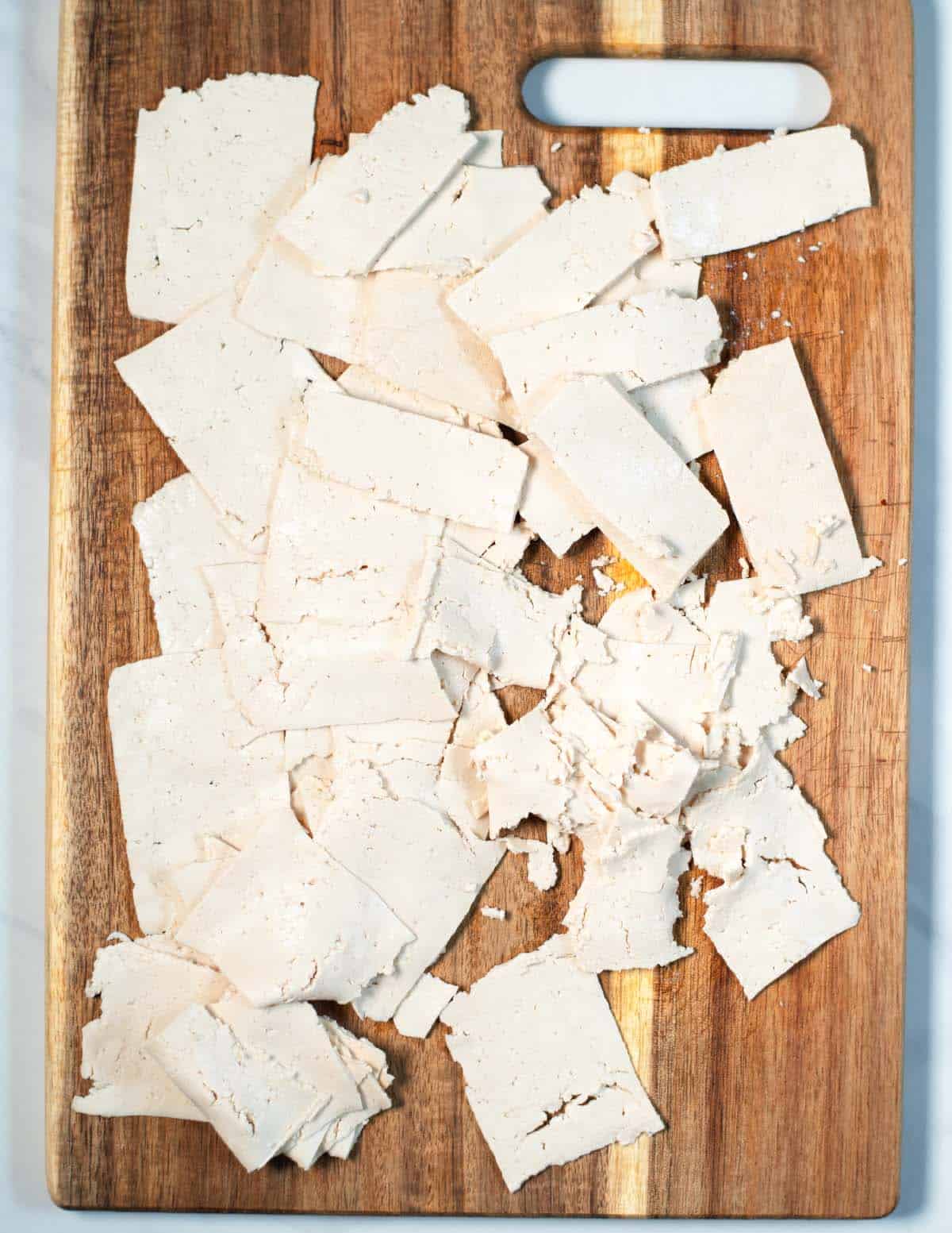 Shaved Tofu on a cutting board.
