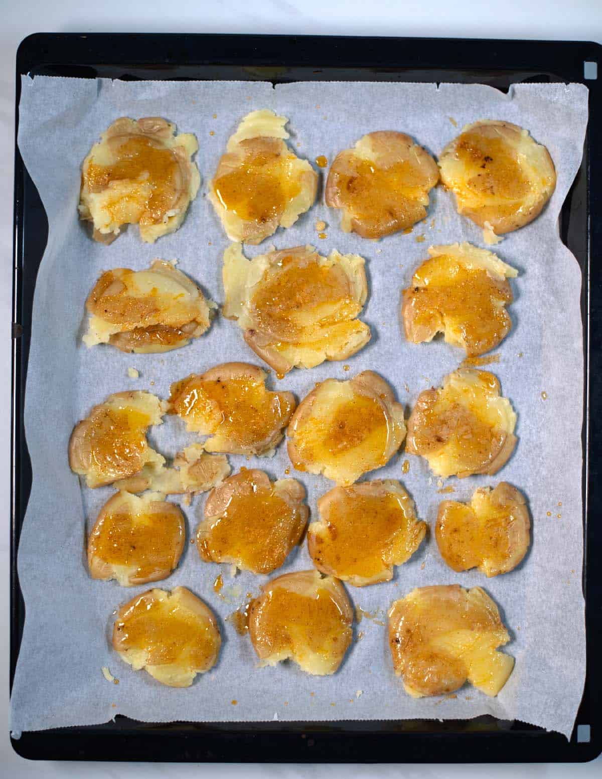 Cooked potatoes are smashed on a baking sheet and then covered in oil and seasonings.