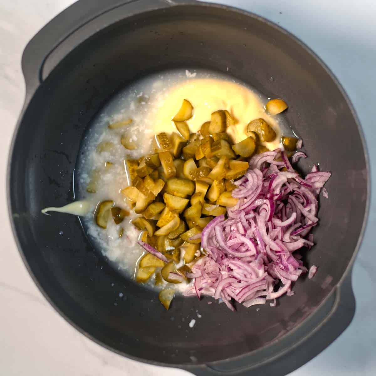 Ingredients for the creamy pickle dressing are given to a large mixing bowl.