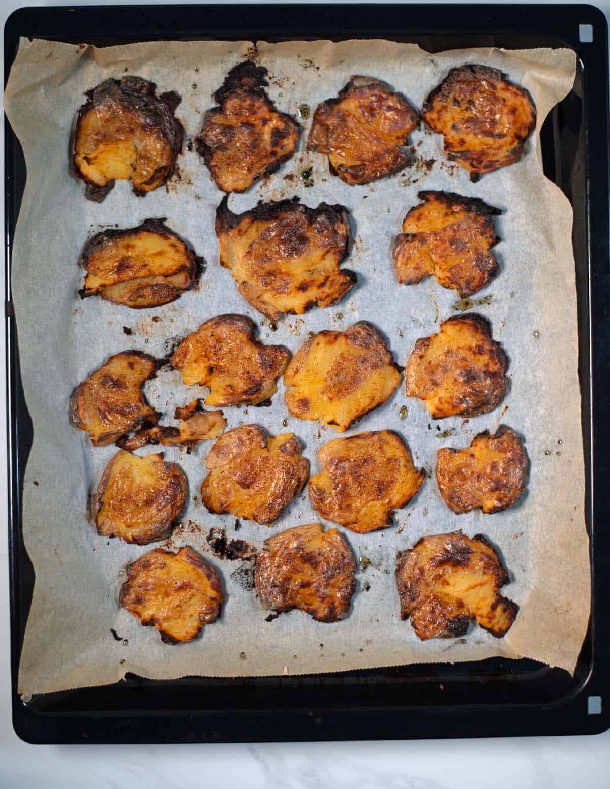 Smashed potatoes on a baking sheet after baking golden brown.