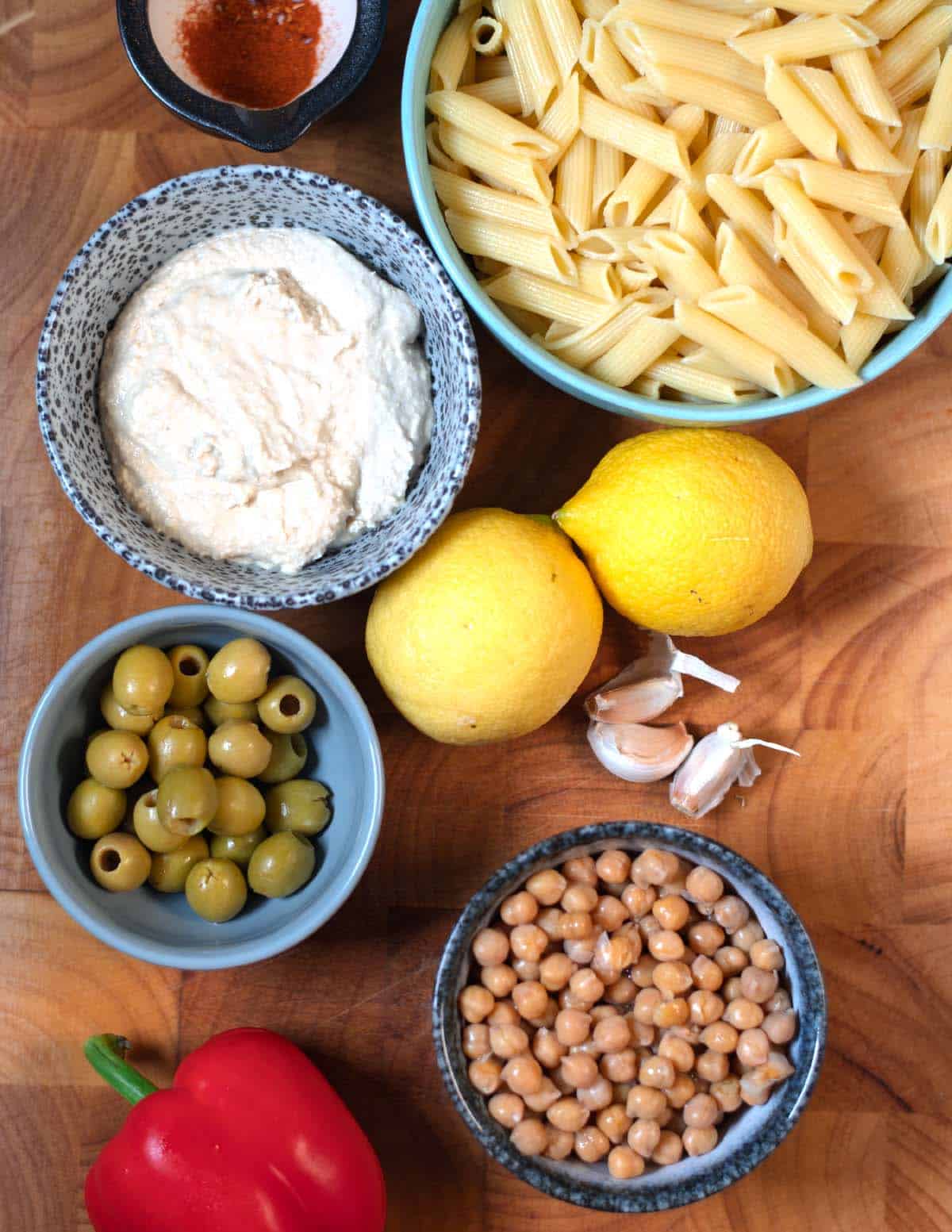 Ingredients needed to make Lemon Pasta Salad collected on a wooden cutting board.