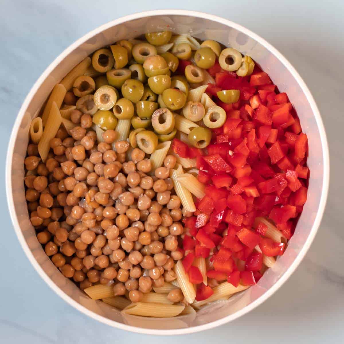 The salad ingredients are added to the dressing in the bowl.